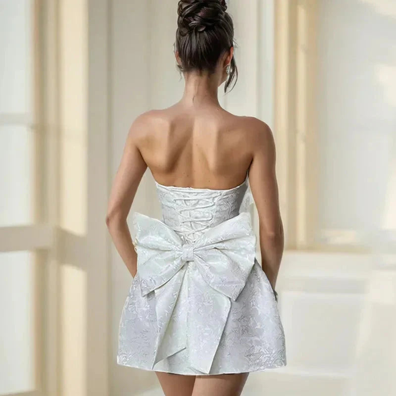 Robe courte jacquard dos nu, sans bretelles, avec grand nœud, en tissu texturé, parfaite pour des occasions décontractées.