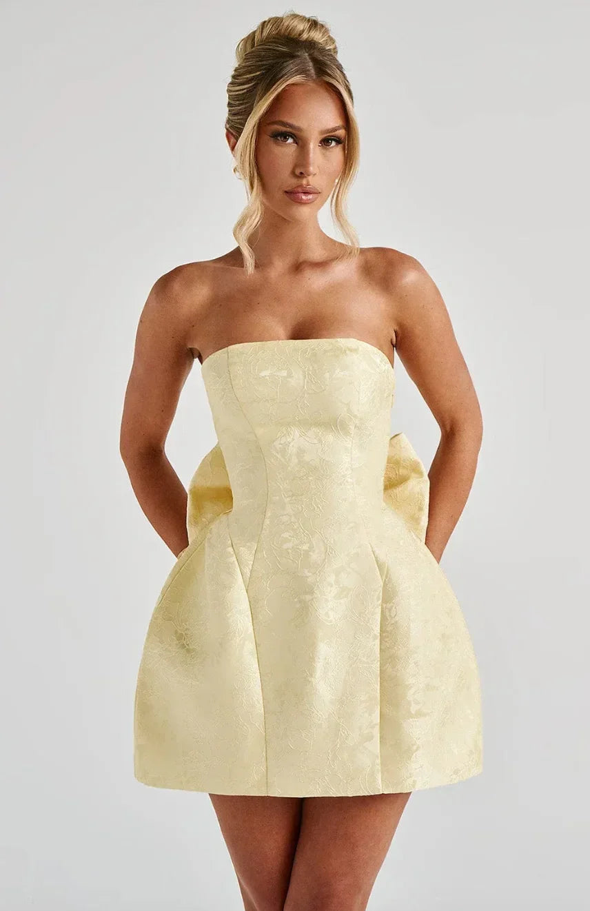 Robe courte jacquard sans bretelles avec grand nœud au dos, en tissu doux et texturé, idéale pour les occasions estivales.