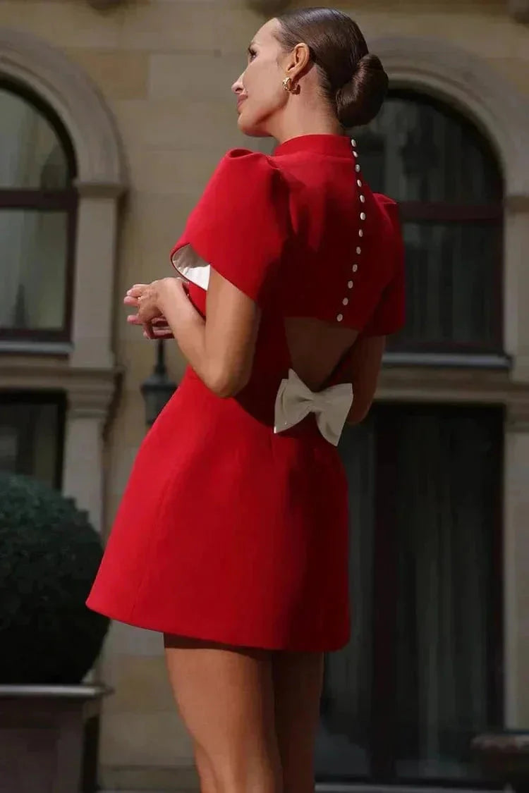 Robe courte unie avec manches structurées et ruffles, silhouette ajustée, parfaite pour les cocktails. Tissu léger et élégant.