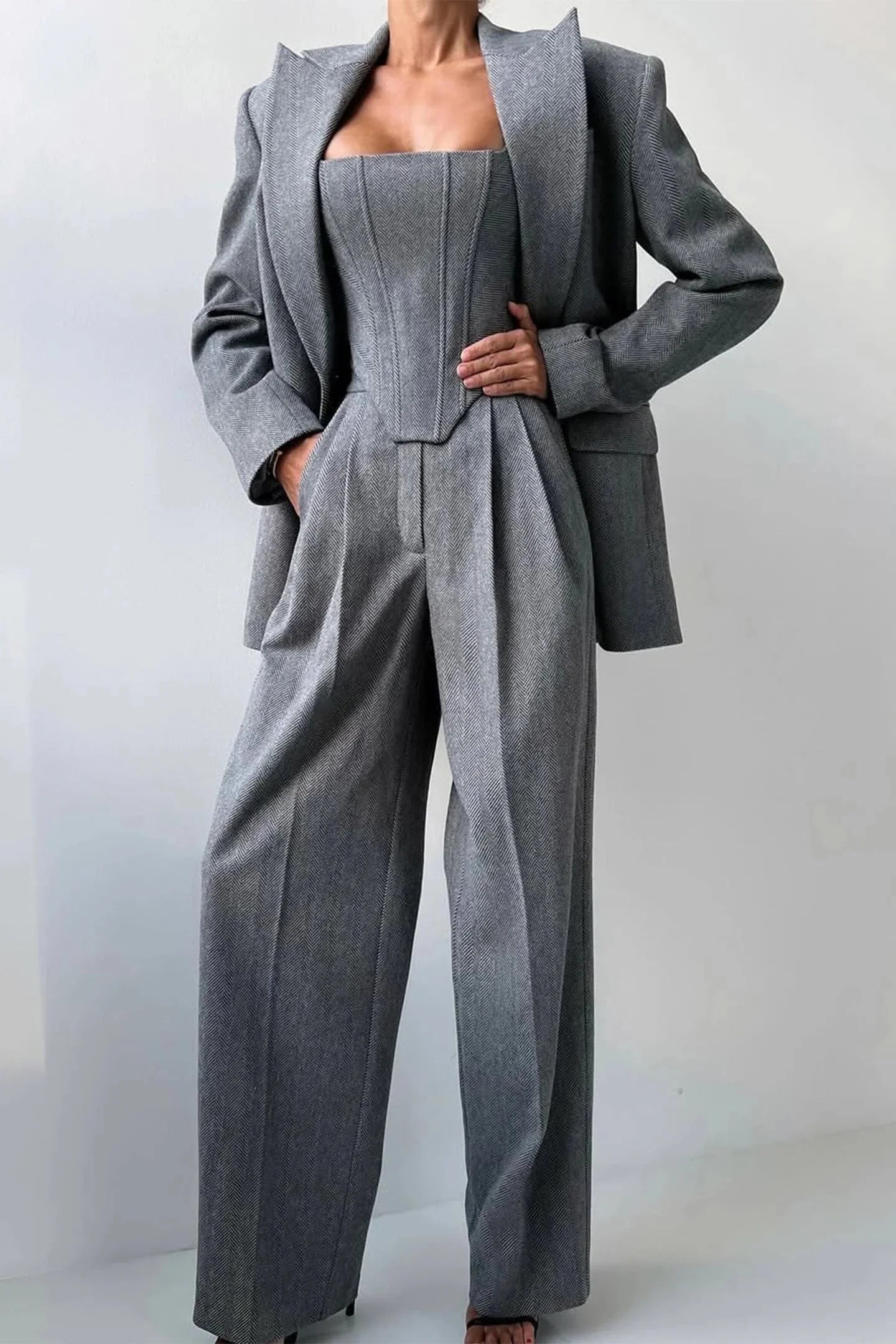 Ensemble femme trois pièces gris, taillé avec un haut ajusté et des détails élégants.