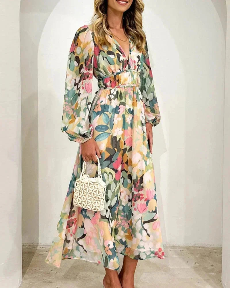 Robe longue fleurie à manches longues en tissu fluide, col en V et taille cintrée, idéale pour un mariage au printemps.